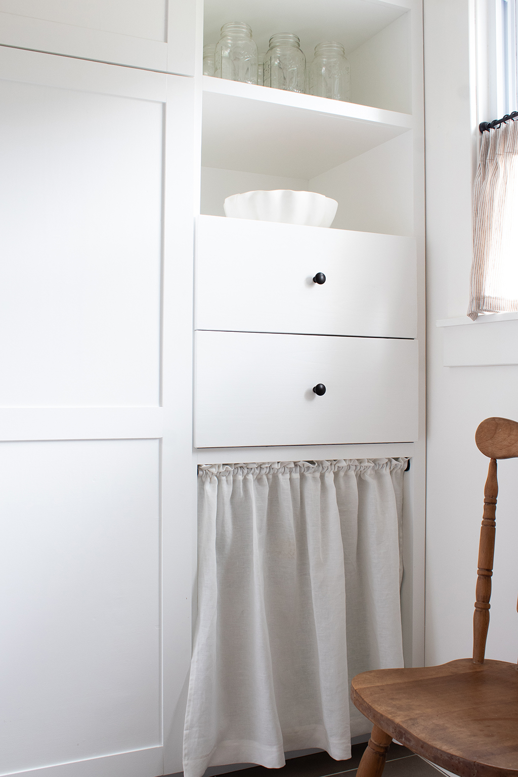 image of white shaker style pantry cabinets with white linen cabinet skirt