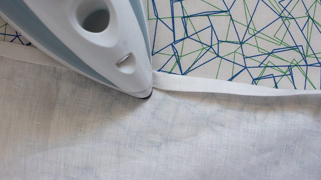 image of iron pressing the edge of fabric for a cabinet curtain hem