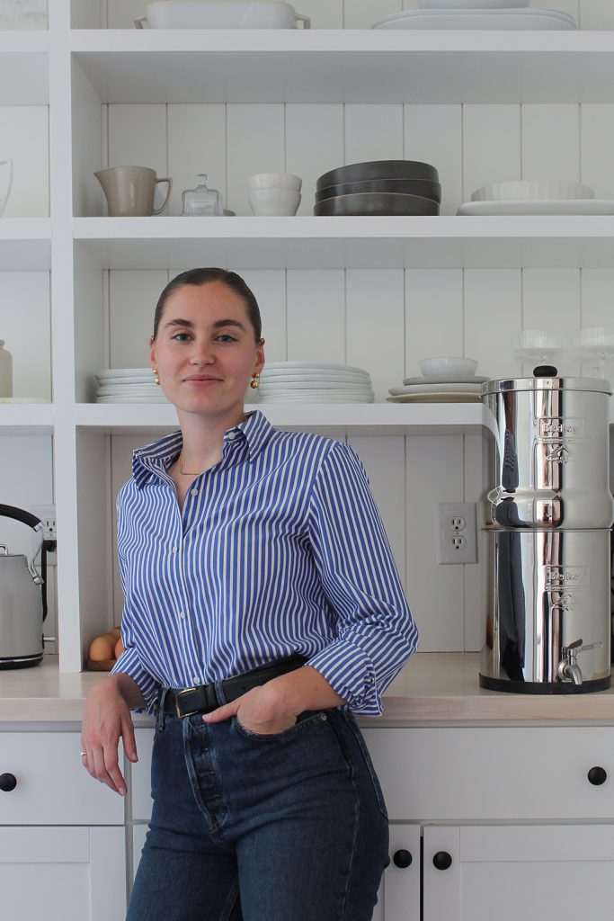 Ruby of Thyme On Our Hands standing against pantry butcher block counter. White shiplap and DIY pantry shelving behind her