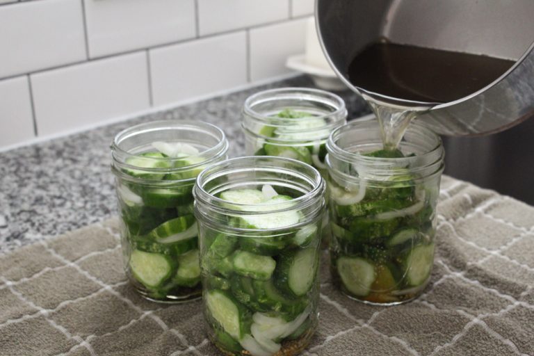 Pouring pickling liquid into pints of bread and butter pickles
