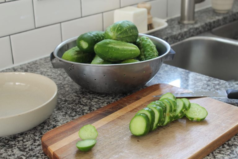Sliced garden fresh pickling cucumbers on wooden chopping board