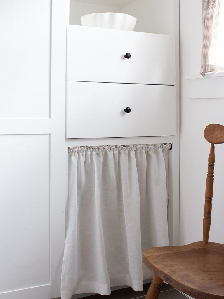 image of white shaker cabinets in pantry with DIY simple linen cabinet curtain hiding clutter