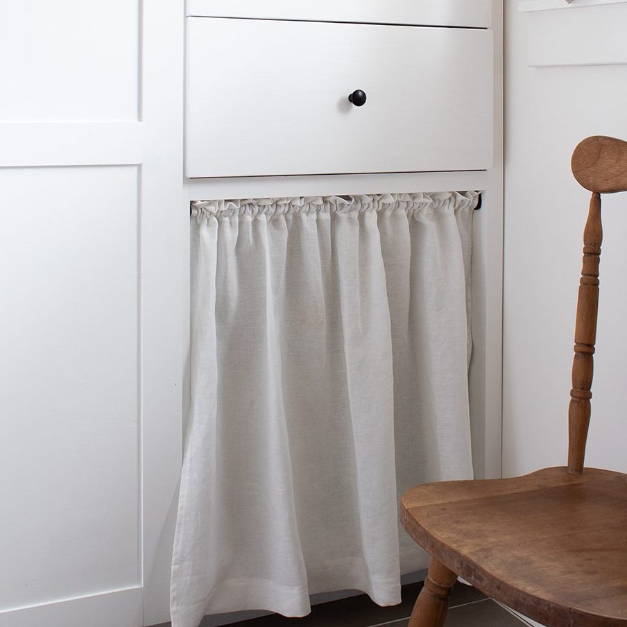 image of white shaker cabinets in pantry with DIY simple linen cabinet curtain hiding clutter
