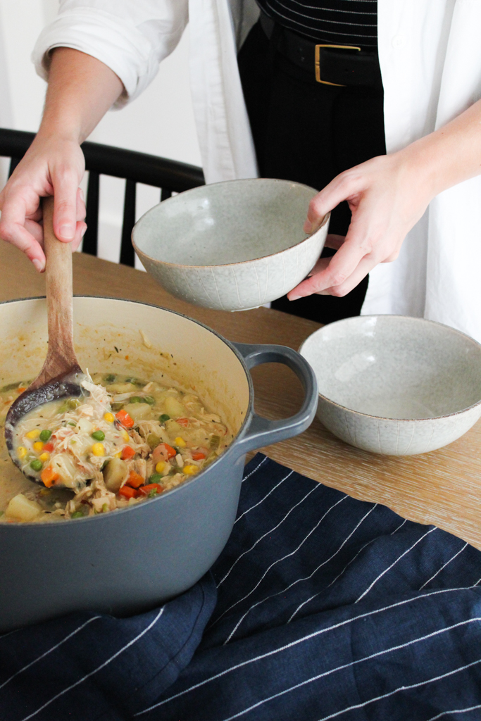 Spooning Chicken Pot Pie soup into bowls at table