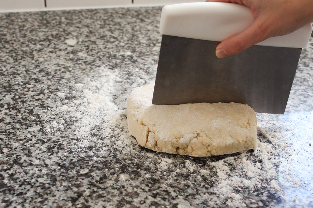 Quartering homemade biscuits dough with bench scraper