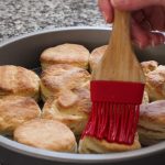 Brushing butter on top of homemade biscuits