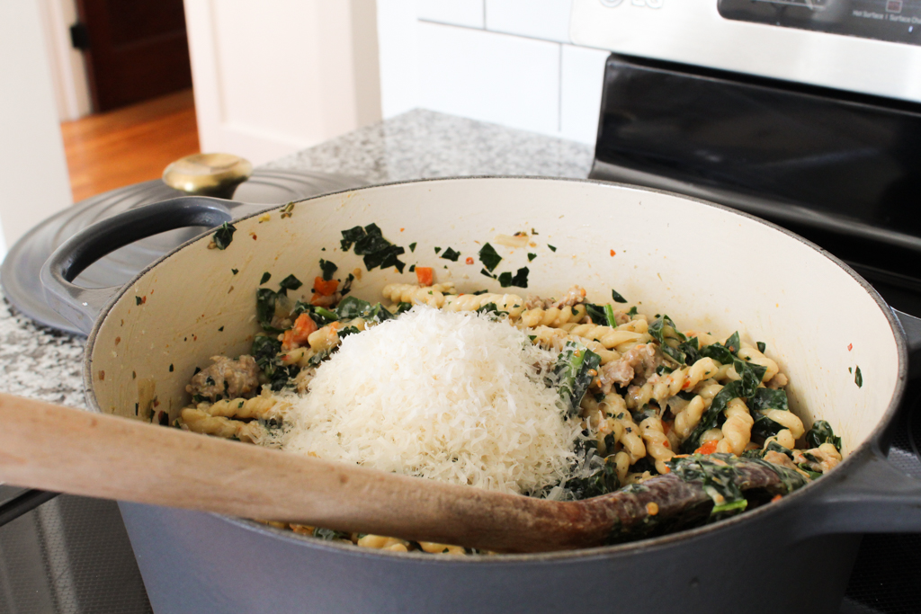 Adding grated parmesan to One Pot Pasta with Sausage and Kale