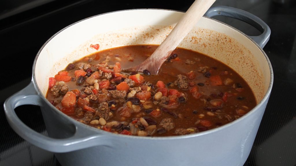 simmering chili on the stove in a dutch oven