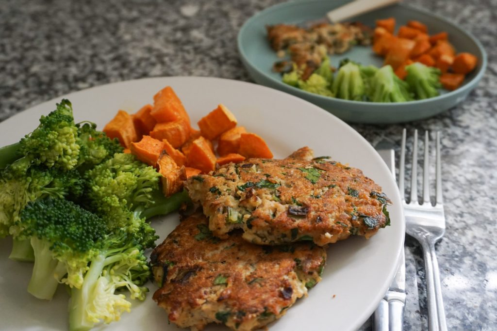 Two plates with easy salmon cakes, roasted sweet potatoes, and broccoli for a quick lunch ideas for moms