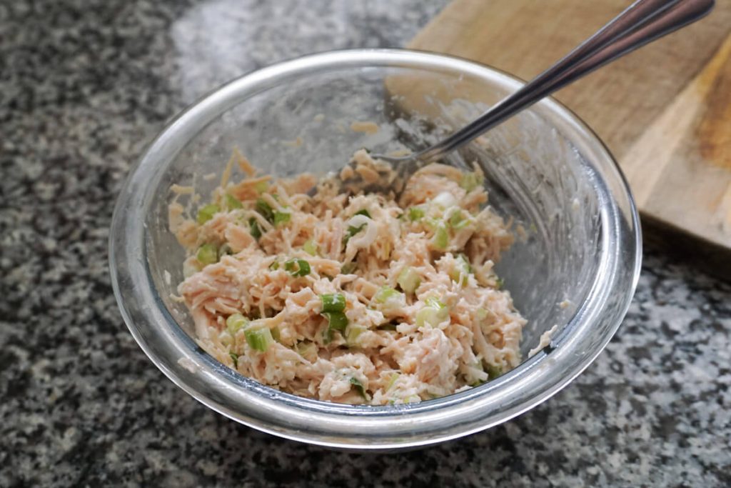 Easy canned chicken salad in a mixing bowl with mayo added