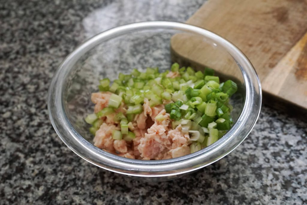 Quick chicken salad in a mixing bowl with green onion and celery