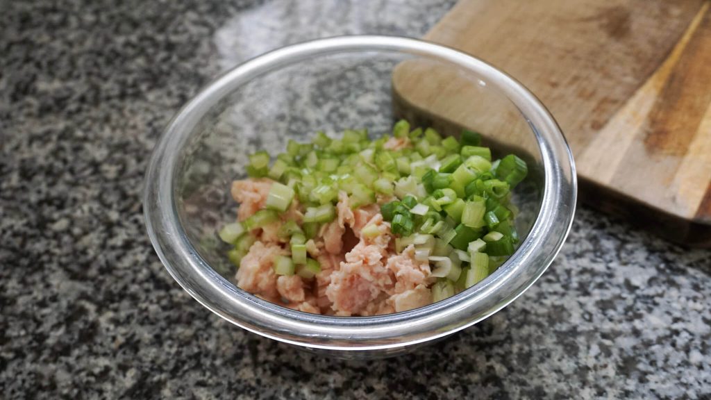 Quick chicken salad in a mixing bowl with green onion and celery