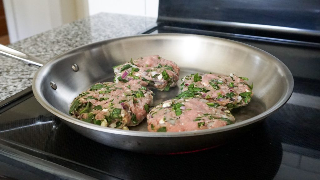 Greek turkey burgers cooking in a skillet for a quick weeknight dinner