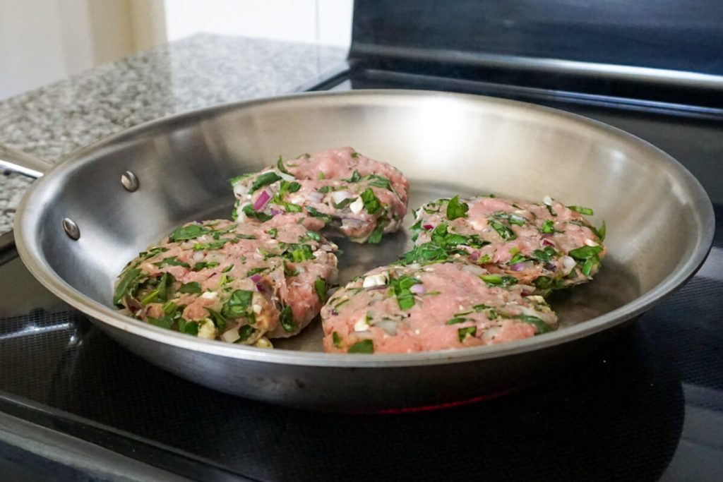 Greek turkey burgers cooking in a skillet for a quick weeknight dinner