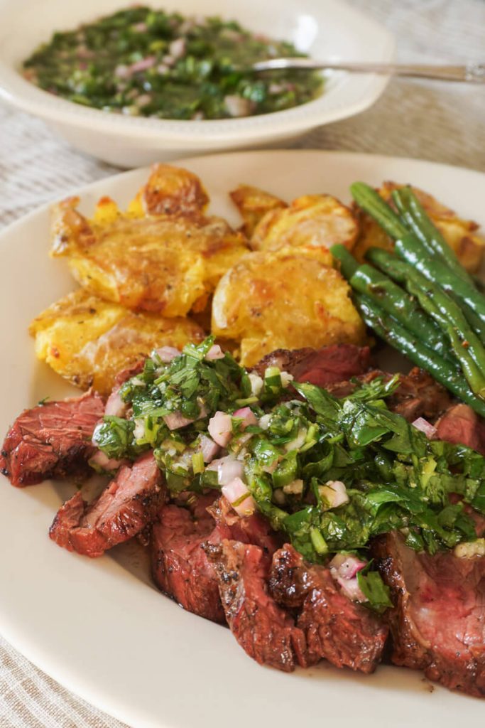 Zoomed in shot of chimichurri sauce on top of grilled steak for easy summer meal idea