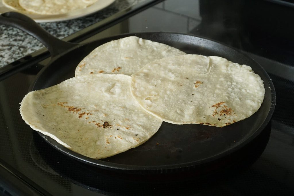 Warming corn tortillas on a comal for fish tacos