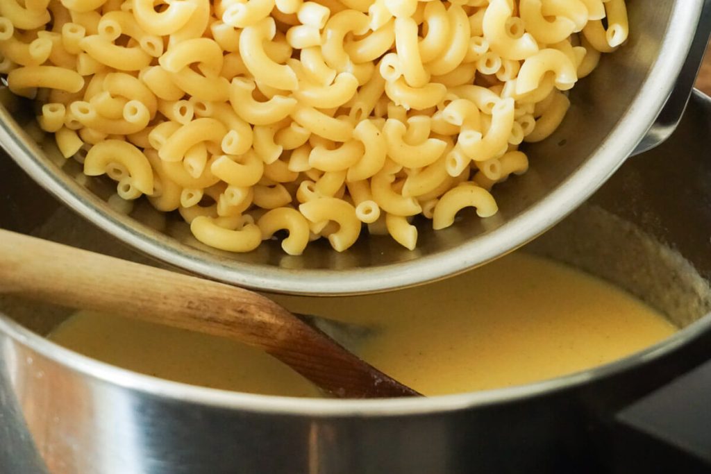 adding noodles to stovetop macaroni cheese