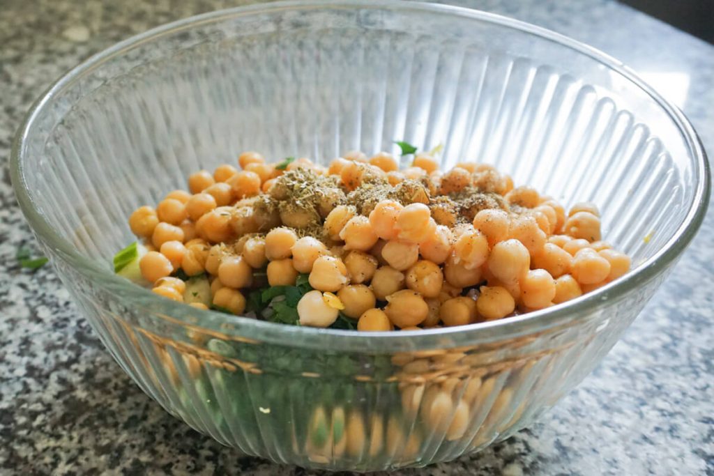 mixing ingredients for chickpea cucumber salad in bowl