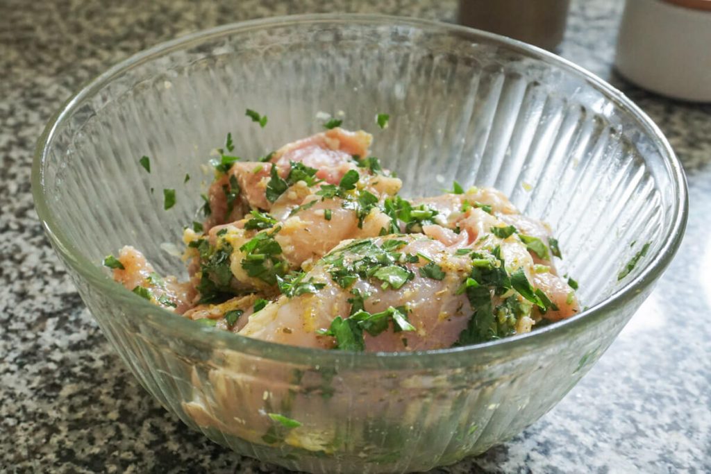 greek chicken marinating in lemon parsley garlic marinade