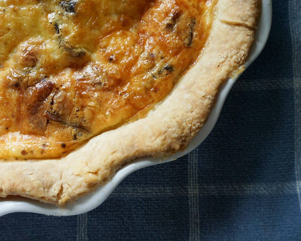 Close up shot of quiche with homemade crust in pie dish