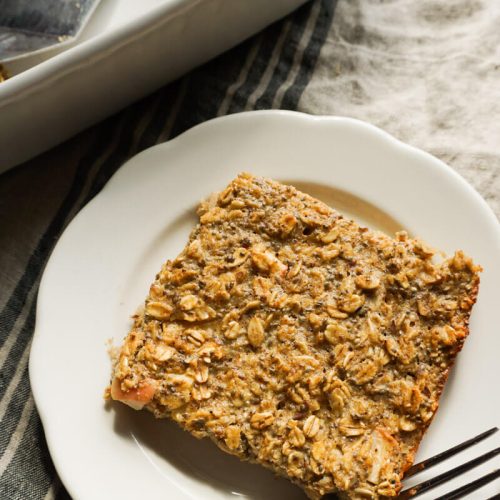 slice of apple pie baked oatmeal on plate next to prepared 9x13 dish of fall make ahead breakfast idea